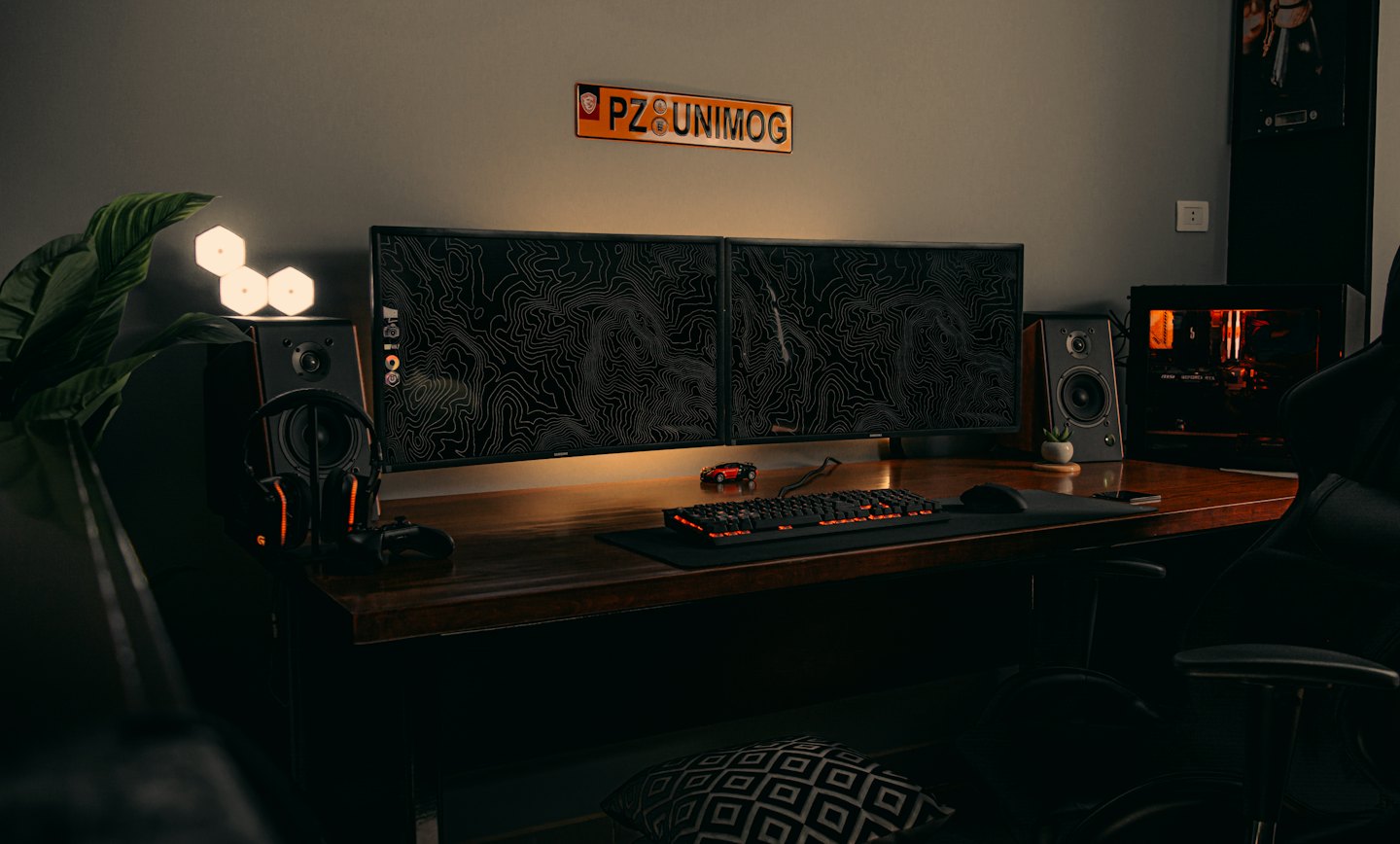 Configuración moderna de ordenador con dos monitores sobre un escritorio oscuro.