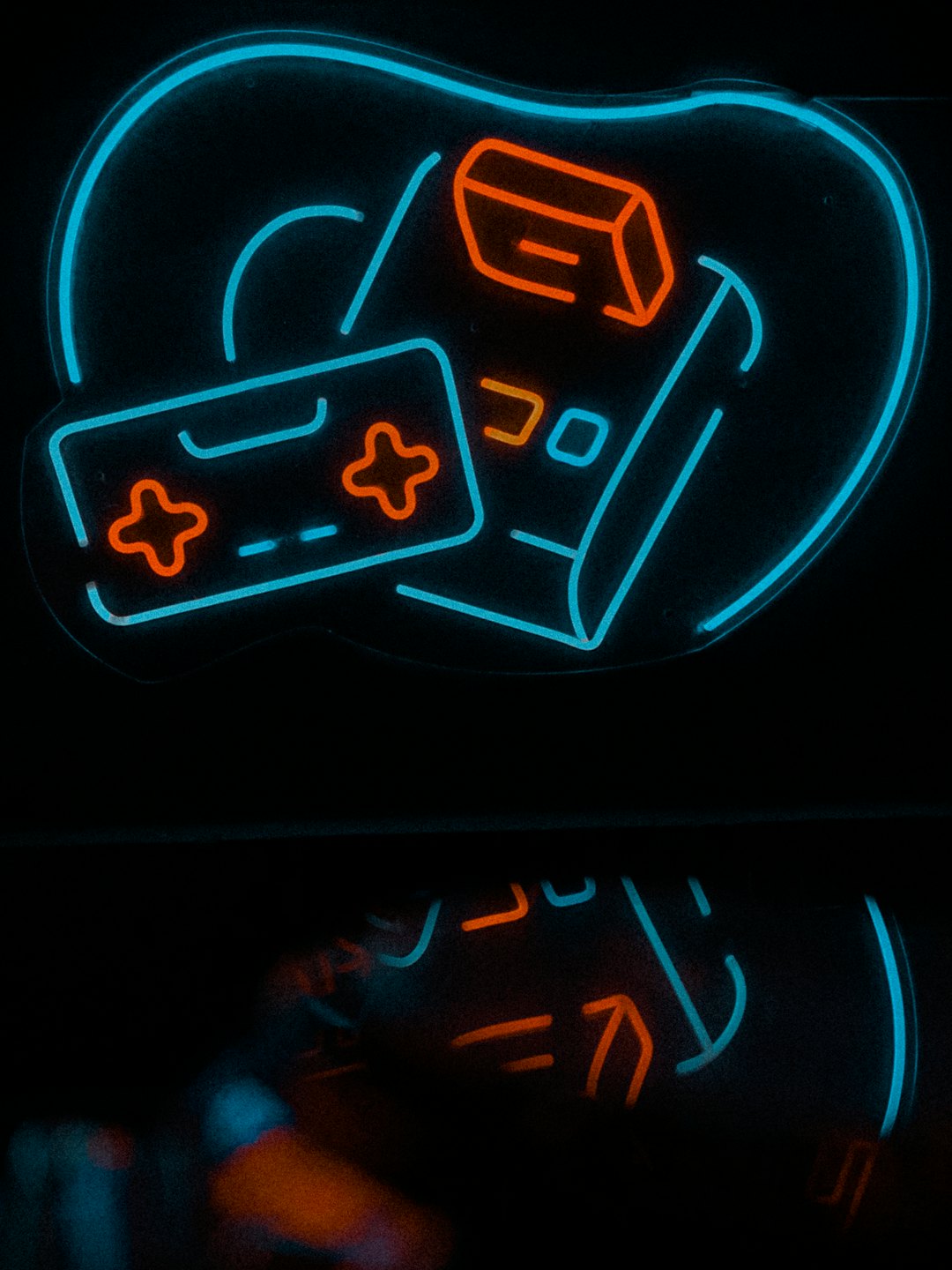 Iconos de videojuegos de neón brillan en una pared oscura sobre su reflejo.