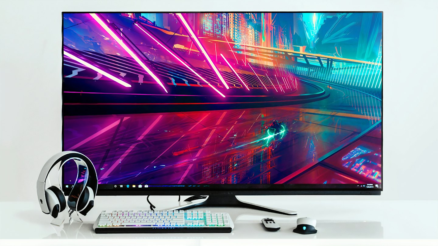 Monitor para videojuegos con teclado y auriculares sobre un escritorio blanco.