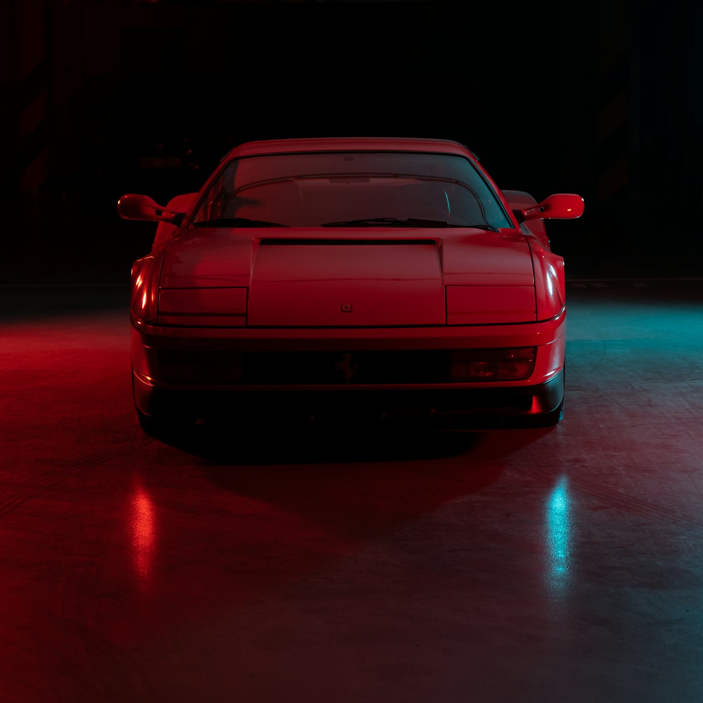 Un coche deportivo vintage rojo aparcado sobre un suelo de hormigón.