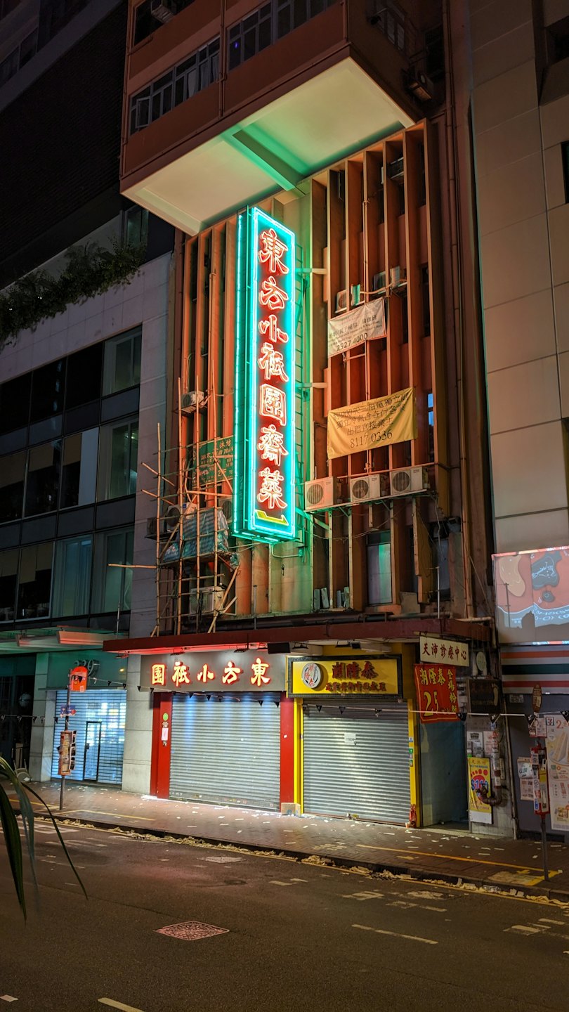 Una calle de la ciudad por la noche con edificios y tiendas iluminados.